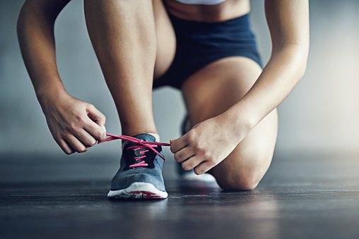 Mulher amarra os cadarços de seu tênis de corrida